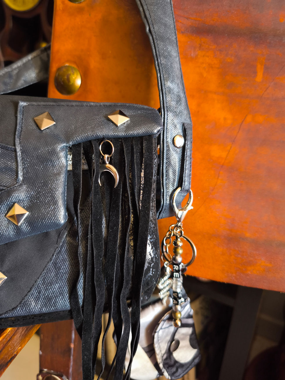 Detail of the Reviva Sperulla bag with fringe, silver crescent moon and handcrafted keychain with included wallet, made from recycled garments