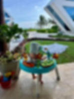 a baby looks at palm trees while sitting in a baby activity table