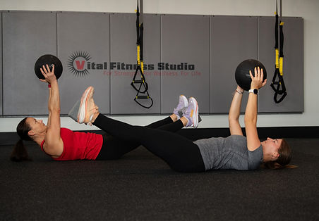 two members laying on their backs lifting weights above their heads