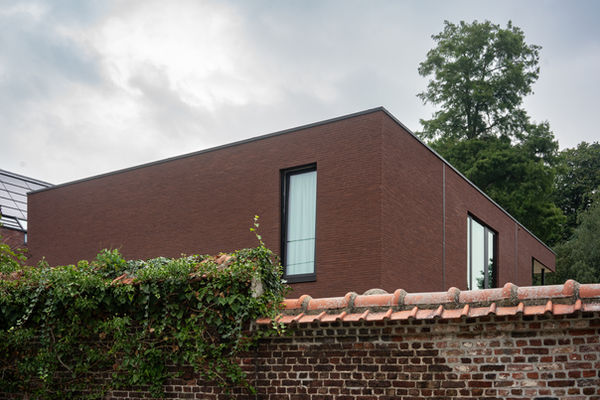 Achter de prachtige kasteelmuur van Tielrode ontdekt men een eigentijdse woning met stijl, ontworpen door Pierrick Architect. Deze moderne woning, verstopt voor nieuwsgierige ogen, straalt tijdloze klasse uit te midden van historische pracht.

Met strakke lijnen en een eigentijds ontwerp heeft Pierrick Architect op een harmonieuze manier moderne stijl geïntegreerd in de historische omgeving. De woning, subtiel gelegen, onthult een doordachte benadering van hedendaags wonen achter de statige kasteelmuur.

Het eenvoudige karakter van de woning wordt benadrukt door de vloeiende samensmelting met de natuur. Het geheel ademt een sfeer van rust en elegantie uit, waarbij de woning als het ware één wordt met de beschermende omhelzing van de kasteelmuur.