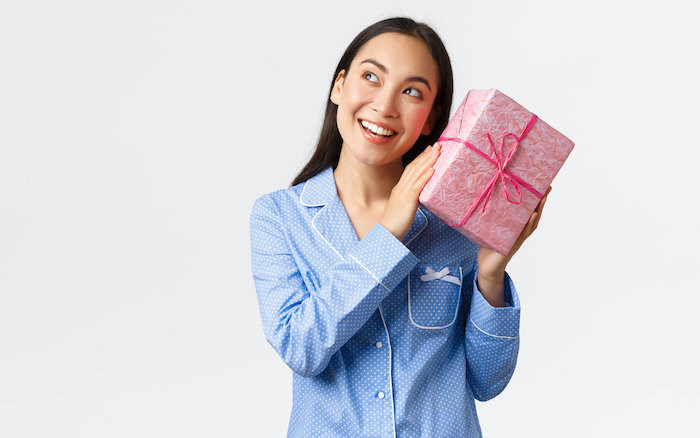 Woman in pajamas holding wrapped gift