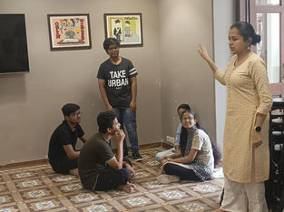 A facilitator guiding a group of teens seated on the floor during an expressive group therapy session focused on emotional awareness and peer interaction.