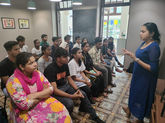 A facilitator conducting a soft skills training session with a group of young adults attentively listening, focusing on communication and self-awareness.