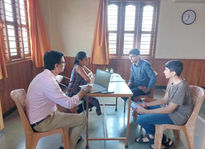 A small group therapy session in progress, where participants engage in structured dialogue guided by a facilitator in a warm, sunlit room.