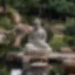 A modern Buddha statue in a Zen garden: a classic symbol of serenity and wisdom that epitomises the teachings of Buddhism.