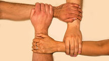 “Four people’s hands holding each other’s wrists to form a square, symbolizing unity, support, and connection.