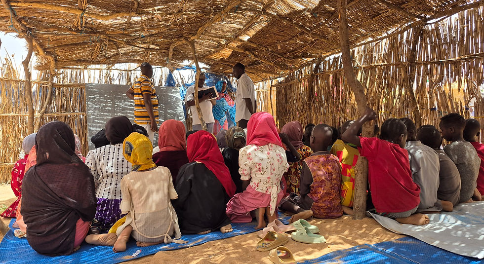 A class of preschoolers sitting on the ground in a thatched school