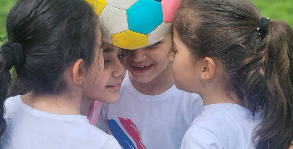 Four girls balance a soccer ball between their heads
