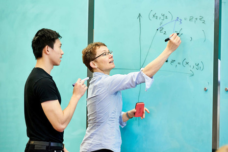 Lecturer teaching mathematics to student using whiteboard