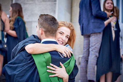 Female hugs male student in graduation gown