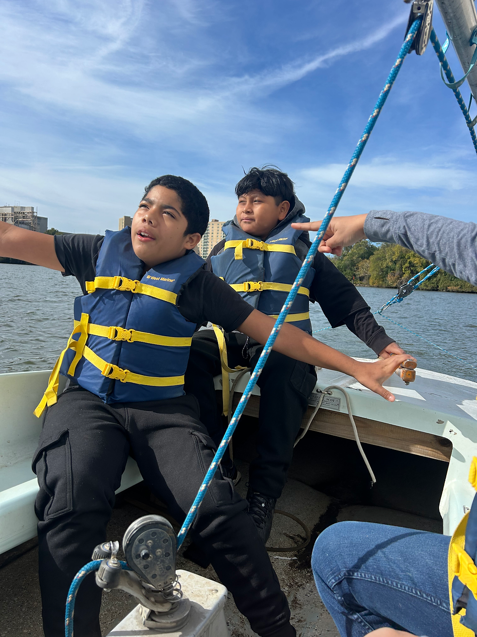 Students share the tiller of a Flying Scot as they sail down the Potomac.