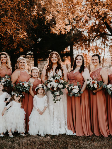 Bride with bridesmaids and flower girls outdoors