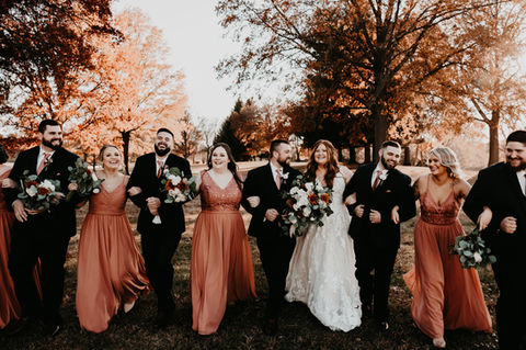 Bride, groom, and wedding party walking in autumn