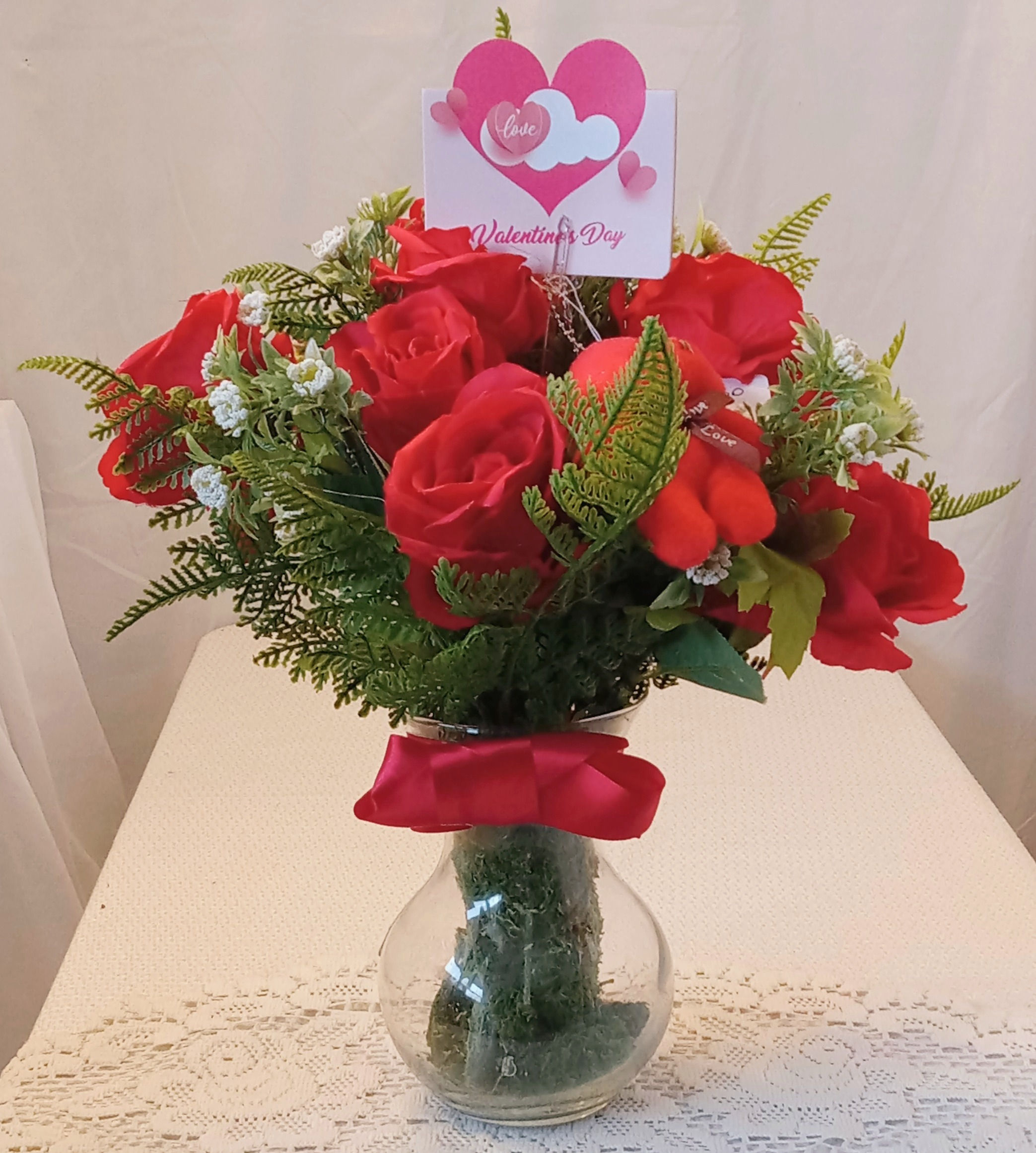 A Dozen Red Roses With Baby's Breath And Green Ferns In A Glass Vase