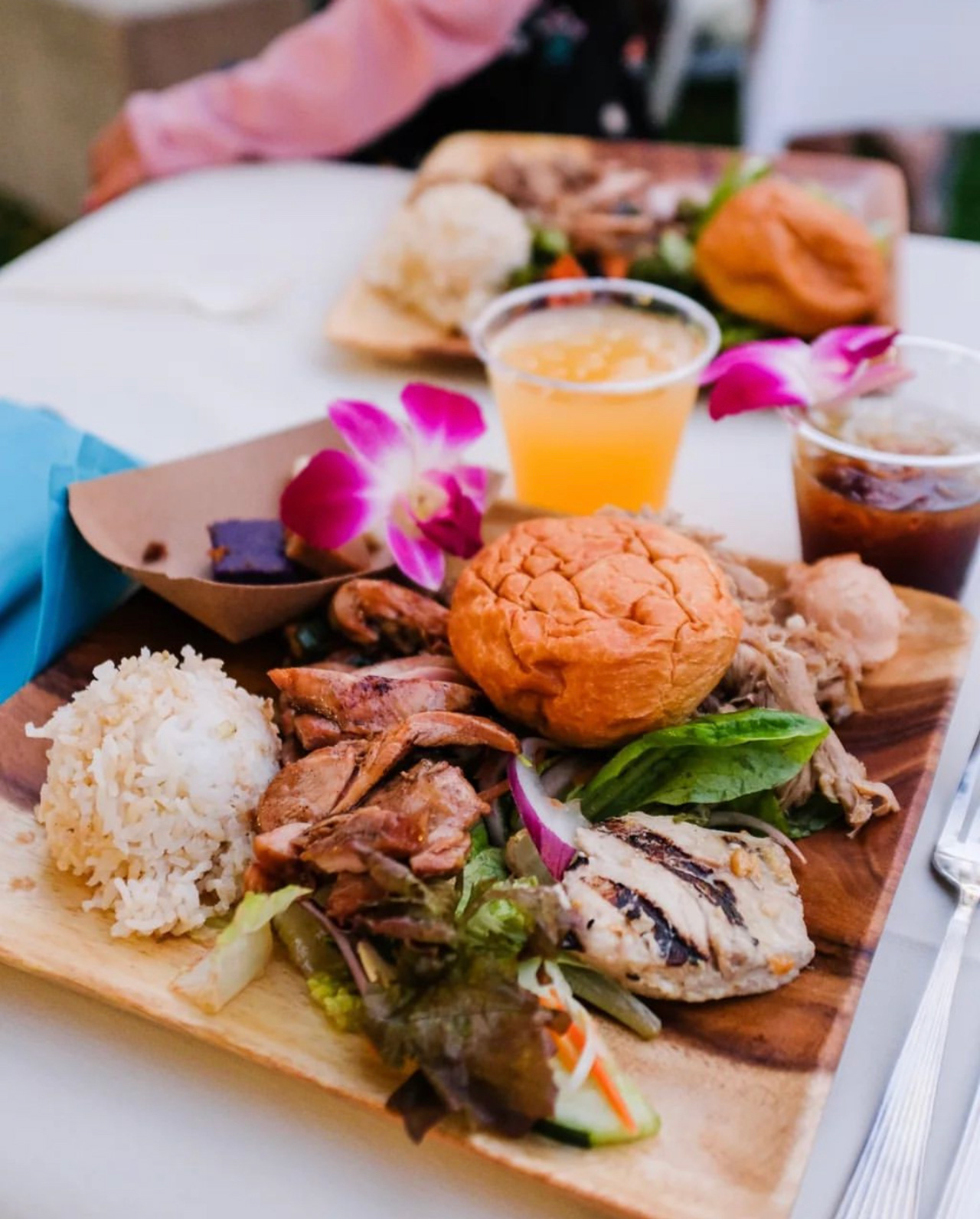 A luau dinner plate with kalua pork, rice, fish and a roll
