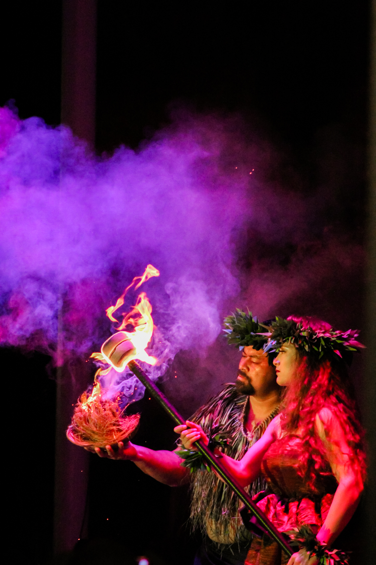 A fire dancer on stage in purple light