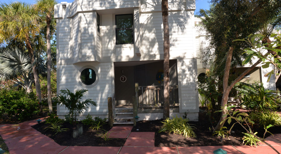 Landscaped walkway, condo, palm trees and flowers