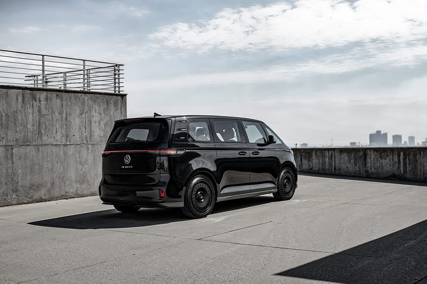 Black Volkswagen I.D. Buzz with forged turbine-style wheels parked on a rooftop with city skyline in the background.