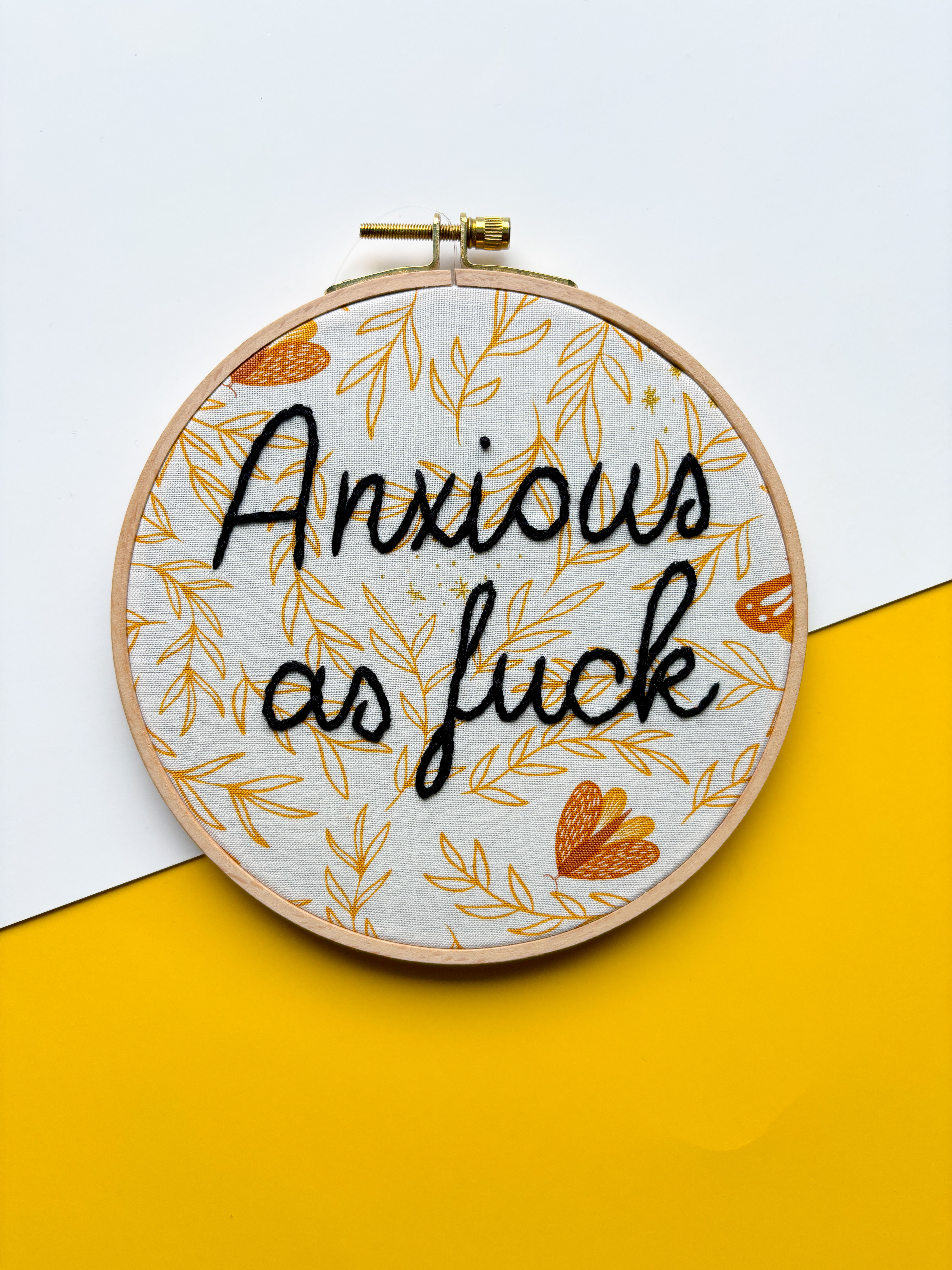 Embroidered hoop art with text Anxious as fuck on yellow and white