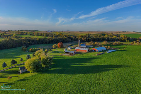Aerial view of a farm with green fields and blue sky background.