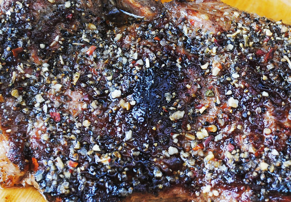 Close-up of a grilled steak with a peppercorn crust, glistening with juices, showcasing a rich brown and black seared surface.