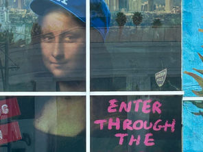 a museum window display with the Mona Lisa in a Los Angeles baseball cap and the message, "Enter Through the Gift Shop".