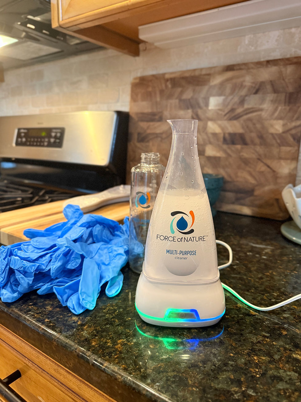 Force of Nature cleaner appliance making a fresh batch on a kitchen counter, next to blue cleaning gloves and a spray bottle