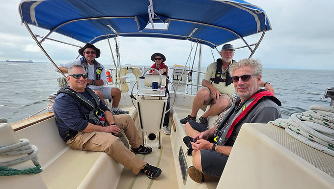 The crew started arriving a little after three on Friday evening and by 5:00, all four students, Peter, Gebhard, Tom and Will, the mate, Captain Jim and I were assembled at the boat and beginning our basic walk-through. After a getting-to-know-you dinner ashore, the crew dispersed to various shoreside motels and we got a good night’s sleep.
On Saturday morning, we continued our examination of the boat and I discussed the roles each student would play over the week - navigator, bosun, engineer and emergency coordinator. We went through the standing orders that would apply to the class and discussed what to do during various emergencies. Then, after lunch, the crew spent the afternoon planning their route from Swan Creek Marina to the C&D Canal. I had already done the route from Lankford Bay Marina to Swan Creek, but I knew that trip would have a lot of detours for training. After a full day, the students once again dispersed to get dinner and pick up any last minute supplies or munchies for the trip.
Sunday morning dawned with a clear sky and, after walking through various sail handling drills at the dock, we went out into the open area near the marina and did a “compass deviation” data run. We took on water and fuel and pumped out, then headed out for the Chester River. After getting in the river, we set the main sail - despite the lack of wind - and performed COB drills in daylight.
The crew quickly got the hang of doing a COB on Navigator and we continued on our trip, arriving at Swan Creek a little before dark. While the crew continued their navigation preps, I made dinner and we enjoyed it in the cockpit, before settling in for a beautiful sunset and off to bed aboard.
Morning came early and we were underway just after dawn. Will was our “Skipper of the Day” and was able to get us going with a cheerful disposition. Once underway, we discovered that today, much like Saturday, was going to be windless. We proceeded up the Chesapeake Bay, into the Elk River and the C&D Canal.
Jim kept the crew busy doing navigational problems to cement the practical skills that had been taught in the Coastal Navigation classroom. Two and three bearing fixes and running fixes were the order of the day, along with attempts at “doubling the bow” and calculating distance off.
Upon our arrival at Schaefer’s Canal House marina, we found that the current in the canal required us to turn around and make a starboard side approach. The crew handily did the maneuver and we were soon tied up at the dock. While awaiting dinner, the crew continued with their navigation planning. After a meal at the restaurant - literally steps from the boat - we settled in for the night and continued preparations for the next leg of our journey.
Dawn once again found us underway and headed for the Delaware River, with Skipper of the Day Tom leading the process. Watching the sun come up over the bridges on the canal is always a lovely sight. Soon we were in the Delaware River and headed south. We had caught the tail end of the flood tide, so our going over ground was slow at first, but once we were in the Bay itself, we were riding the ebb current and doing more than 7 knots over ground.
Around dinner time, one of the crew noticed that we had not really had a lot of battery charge during the day, despite (once again) motoring. I was alerted and did some basic troubleshooting, deciding the problem was a faulty battery in our main house bank. I removed that battery from the bank, the charge came up and we continued.
When I came back on watch at 9:00 PM, the crew reported that we still weren’t getting a battery charge and that, since the sun had gone down and the solar panel had stopped supplying power, the battery charge had decreased even more.
By this point, we were about 10 miles out in the ocean, heading for our northern “offshore” waypoint. Knowing that without a functioning charging system, we would soon be without lights and navigational equipment, I made the decision to turn around and head back into Lewes, Delaware. Tom was on the wheel when we entered into the Lewes channel at about 2:00 AM and, with some guidance from our Lewes-based Captain Hattie, we found ourselves tied up at the Lewes Town Dock by three. After bringing on shore power to recharge our batteries, we all crashed into a heavy sleep.
Subsequent troubleshooting identified the problem as a bad ground connection between the Balmar alternator and the engine. With some help from the crew, I was able to replace the corroded connection and subsequent testing indicated that the problem was (probably) resolved.
However, since there was no way to determine if the problem was actually fixed and having wind and weather predictions that indicated going south would be wet and lumpy, we discussed our options and decided to do the next leg to Annapolis back the way we had come. That way, if the problem recurred, we would not be offshore with limited options for support. Skipper of the Day Peter was in charge and we took the opportunity to do some sailing exercises before continuing our voyage. We were able to perform controlled gybes, tacking with the cutter rig (a set of exercises that would prove fortunate before the end of the trip) and even doused the mainsail while still sailing on the headsail, an important offshore skill.
Once underway, we sailed up the Bay on the headsail, with the wind behind us on our port quarter. Over the hours, the wind and waves increased and we were finally sailing well. Unfortunately, we finally hit a combination of course and wind direction that precluded the further use of the headsail and we had to roll it in, continuing on the engine. By this time, we were stemming the outgoing tide and our speed over the ground was down in the 3 knot range, despite a satisfactory 5.5 though the water.
We had had storms predicted for the day and at about 5:00, we hit a massive storm cell that did not want to let us pass. Unlike most cells that tend to move, allowing us to basically hold position and let the cell leave us, this one was forming over the river and staying in one place. The only way out of this cell was through it, so through it we went.
It took over two hours for us to pass from one side of the cell to the other. While in it, we saw wind gusts of more than 40 knots and a pretty consistent 30 knots that shifted from our stern to our bow and back to our stern. When the wind was on our bow, our speed over the ground would drop to 1.5 knots, prolonging the time we spent in the cell. With shoals to our port and the shipping channel to our starboard, we had limited options for our course and the crew did their best to hold us on our heading. At points, the heavy rain kept the visibility down to under one-half mile and blanked out the radar into a huge mass of red.
Finally, around 7:30, the sky cleared, the rain stopped and the wind dropped back down to a respectable but manageable 20 knots. We continued our trip and were in the C&D Canal a little after 9:00.
We headed into the canal with the current on our bow, but by the time we had crossed the 15 or so miles, the current had changed and was now running with us. Coming out of the C&D canal, we followed our navigation plan down the Bay, watching the water spread out and the clouds lighten above us. Lightning to our west continued to show us where the big storms were.
At about one in the morning, the clouds had cleared to the point that we could see the moon, which was going through a near total lunar eclipse. For an hour or more, we watched the moon disappear and then reappear. As the lunar show wrapped up, the clouds thickened and darkened. It was as if the entire show had been put on, just for us.
As we traveled down the Upper Chesapeake Channel toward Annapolis, we passed not one, but two aids to navigation that were not working. Checking the Local Notice to Mariners determined that one had been listed, but the other was not. We reported that condition after we got back to Lankford Bay Marina.
As the sun came up, we found ourselves passing under the Annapolis Bay Bridge and moving into the large ship anchorage area outside Annapolis Harbor. Since we didn’t want to go into Annapolis until after noon, we continued down the western shore to the Thomas Point Shoal Light, then cut across the bay to the Bloody Point Bar Light on the eastern side. Once there, we turned around and went back to the mouth of the Annapolis Harbor channel. All morning, the water had been flat enough that we could see individual clouds reflected on its surface, but just as we got to the red #2 buoy, we began to see some ruffling and little wavelets. We took this as a hopeful sign.
That afternoon, the students took the ASA-106 written exam and all successfully passed. To celebrate, we took a water taxi into town and showers were taken. Some of the crew wondered about carrying their shower gear to dinner afterwards, but as I explained, Annapolis has a long history of sailors wandering around with their shower gear tucked into a bag or backpack and the locals hardly give it a second glance. This trip was no exception.
After dinner at the Iron Rooster (or was it breakfast? IR has a very eclectic menu), we eventually all made our way back to the boat. We found that the batteries were holding a great charge and we had no need to top off the house bank before bed. It would seem that the fix applied in Lewes was the correct one (finally!).
Underway in the morning at four AM, we headed out into the Navy Anchorage to do our COB training at night. Gebhard was our Skipper of the Day. We did our Crew Overboard drills by having the two “off watch” people start in their bunks, with their PFDs off but nearby. Then, I would send the rover below to stand in the galley while I turned on the mannequin’s strobe light and tossed it overboard. The helmsman had to stop the boat, start the engine and get the crew on deck, all without losing sight of the mannequin in the water. I can happily report that “Oscar” was successfully rescued all four times and we never ran him over with the boat.
We finished up the COB training just as the sky was starting to lighten with the coming of the dawn and we headed toward the Bridge crossing under power. After passing the bridge, we set the main and the genoa and started sailing to our waypoint, the LP mark near the Love Point end of Kent Island. Because the wind was coming from that direction, we ended up doing a series of tacks up the Bay. We would sail east until the depth sounder read 30 feet under the keel, then tack and run west until we were almost at the Craighill Channel. This was where our tacking practice the previous day really paid off. On our second approach, we actually had a large bulk cargo carrier coming down the channel, so we tacked a little early and finally made our waypoint on that leg. Given that we now had to go directly into the wind, we furled the headsail and slid the traveler over slightly to keep the main from flogging, then motored to our next way point.
After rounding Love Point, we reset our sails and continued to the red 12 buoy in the Chester River. We had to furl our headsail there, but we were able to motor-sail up past the red 14 buoy, where we finally doused our mainsail and motored back to our marina.
Once back in our slip, the crew cleaned up the boat, diplomas were presented, ASA logbooks signed and the crew departed, happy and tired and, hopefully, with knowledge that they would use for the rest of their sailing careers.