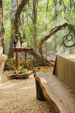 Mesa de comedor al aire libre en Madre Verde, en la selva cerca de Puerto Morelos, preparada para una comida comunitaria del retiro, rodeada de bosque.