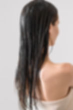 back of woman's head showing her long hair covered with a conditioning mask 