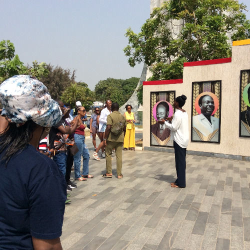 Visitors exploring an outdoor portrait display during an Accra city tour