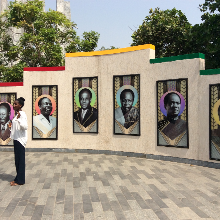 Portrait murals along a wall during an Accra city tour
