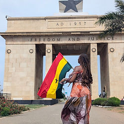 Lady waving Ghana flag at blackstar gate