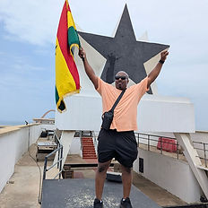 man holding ghana flad ontop of Blackstar gate