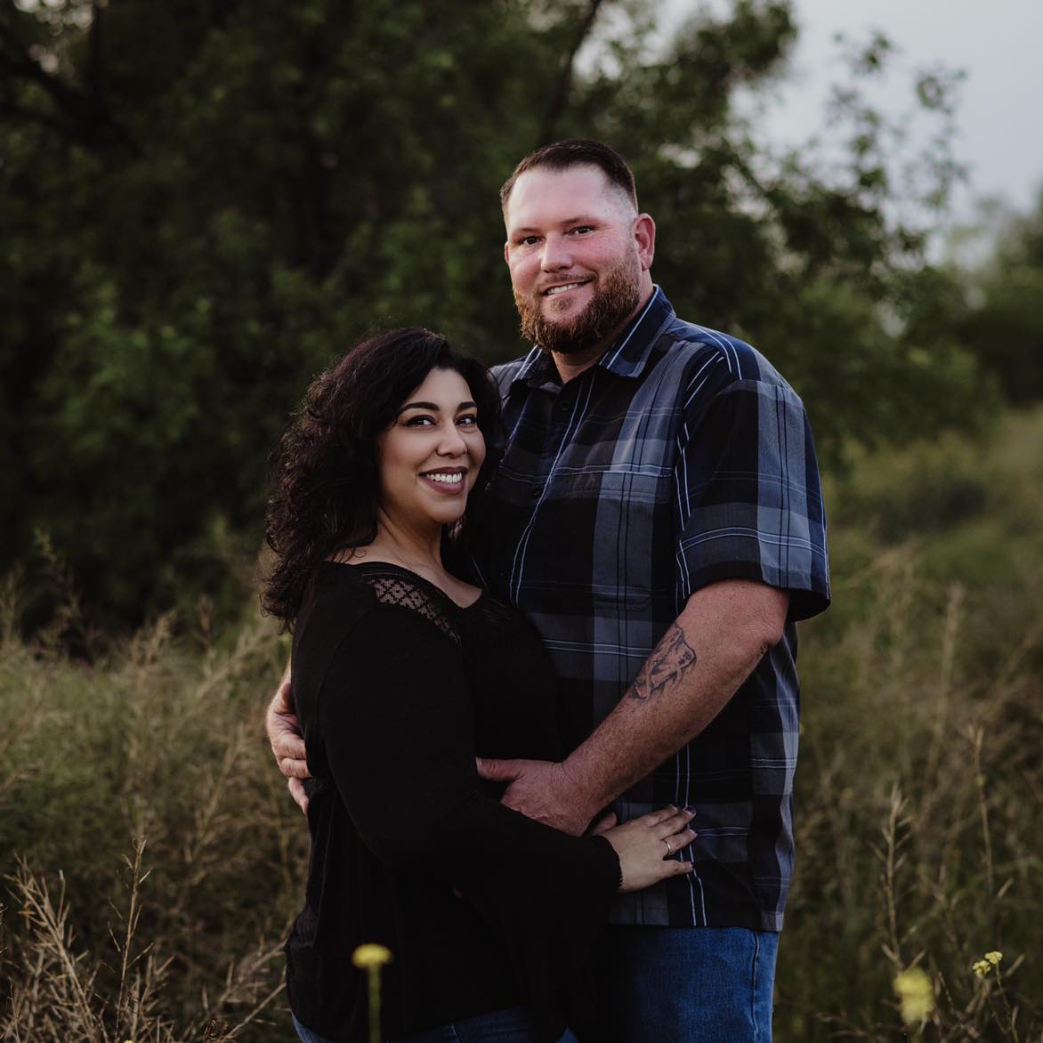 Katie Rodriguez Brockie standing a warm embrace with her husband.
