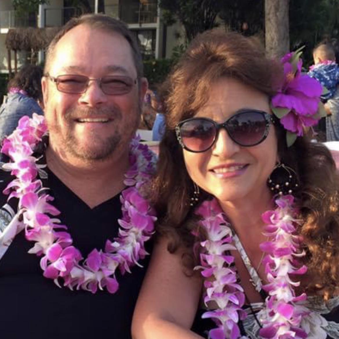 Christina Hernandez Risdon and male companion smiling with pink and white leis. 