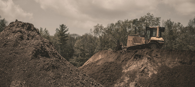 yellow and black heavy equipment on brown rocky hill under white cloudy sky during daytime