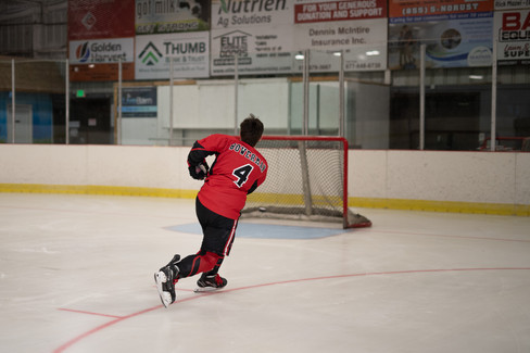 Senior Portraits of a senior hockey forward in full stride wearing his game jersey for Envisions Photography Studio.
