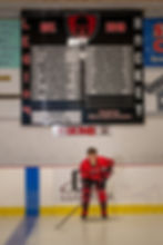 Senior Portraits of a senior goalie crouched in the crease staring down the lens with Envisions Photography Studio.
