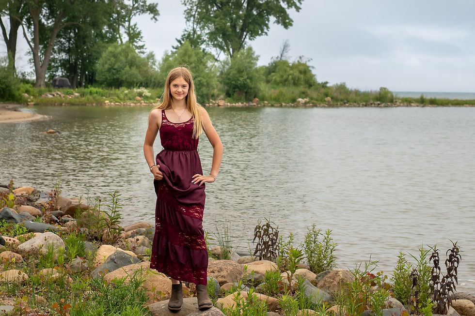 Playful shot of the student dipping her feet near the calm water edge at the Port Hope shoreline