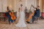 Harp and cello perform as a bride walks the aisle; groom waiting in an elegant ceremony room.