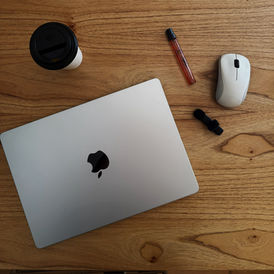 desk with a macbook, mouse, lipgloss and coffee cup