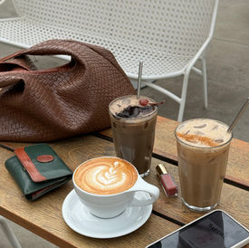 table with coffee, phone, makeup and purse