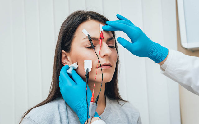 "Prueba de conmoción cerebral nerviosa. Una paciente mujer está con electrodos conectados a la frente mientras se realiza la prueba. Esta prueba mide la actividad eléctrica del cerebro para evaluar la función neurológica y detectar posibles lesiones o alteraciones causadas por una conmoción cerebral. Los electrodos registran la respuesta eléctrica del cerebro en respuesta a estímulos específicos."