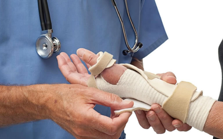 "Servicios ortopédicos después de un accidente laboral o automovilístico. La imagen muestra a un doctor colocando un yeso temporal en el brazo de una paciente, desde la mano hasta casi el antebrazo. El especialista está enfocado en inmovilizar la lesión para proporcionar soporte y permitir la correcta curación de huesos o tejidos dañados."




