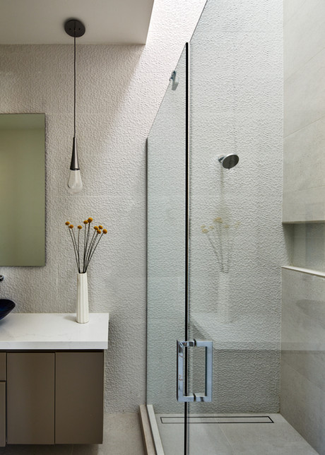 Minimalist Sedona shower with textured tile walls glass enclosure and pendant lighting over vanity