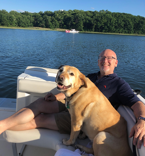 Man on boat with yellow lab sitting next to each other