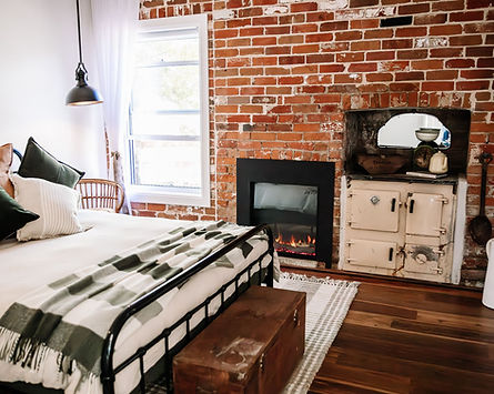 Bedroom with brick fireplace and timber floors at Calabash Waters farm cottage