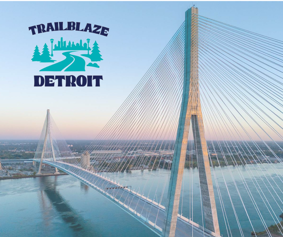 Trailblaze Detroit logo over aerial view of a cable-stayed bridge spanning calm water at sunset under a pastel sky. crossing the gordie howe international bridge multi-use path biking cycling walking running jogging border guide how to