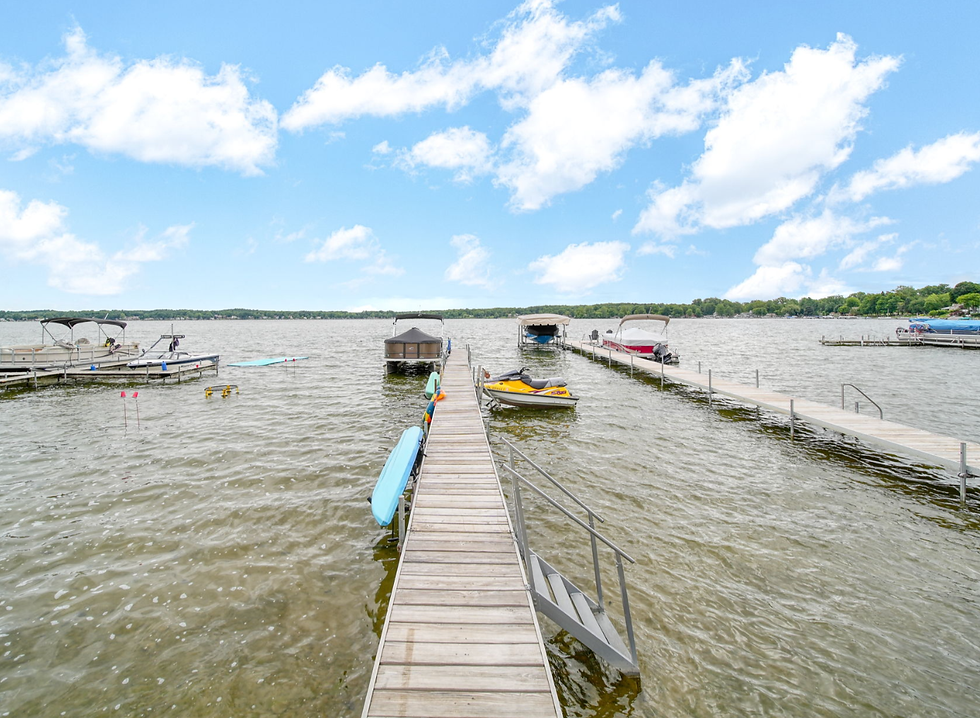 wide landscape photo of a lakeside dock with boats on both sides under a bright blue sky with scattered clouds